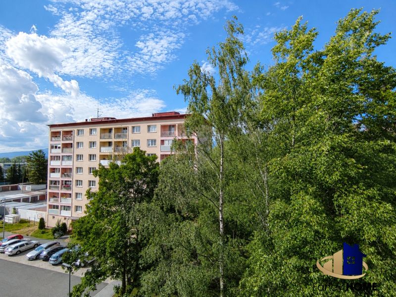 Bytový dom obklopený stromami a parkoviskom na ulici 29. augusta v Poprade.