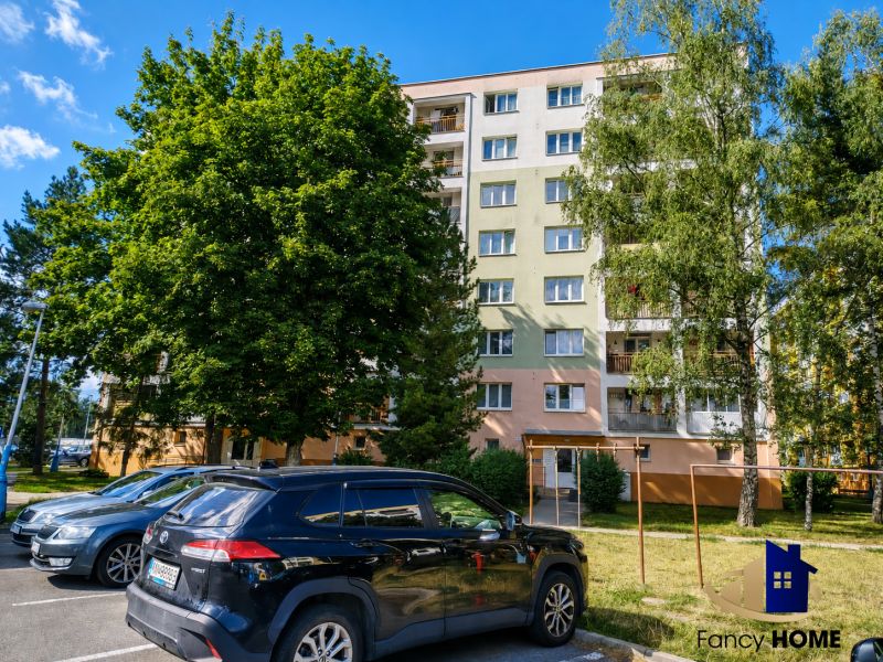 Exteriér bytového domu na ulici 29. augusta v Poprade so zaparkovanými autami.